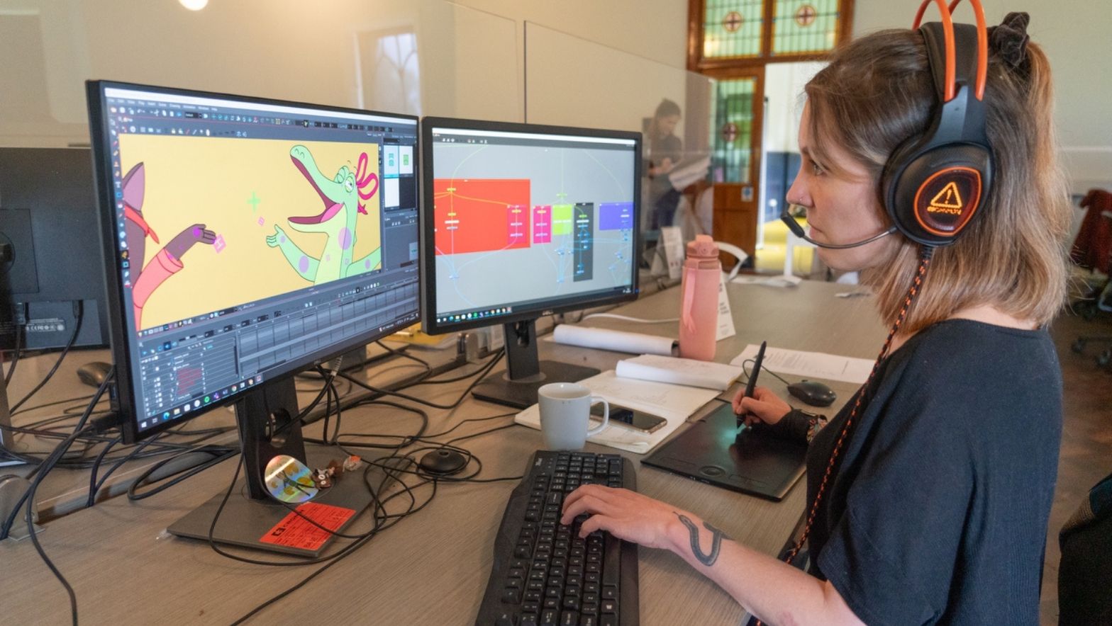 An individual sitting at a computer with a vivid illustration on the screen. The individual appears to be working on the image. 