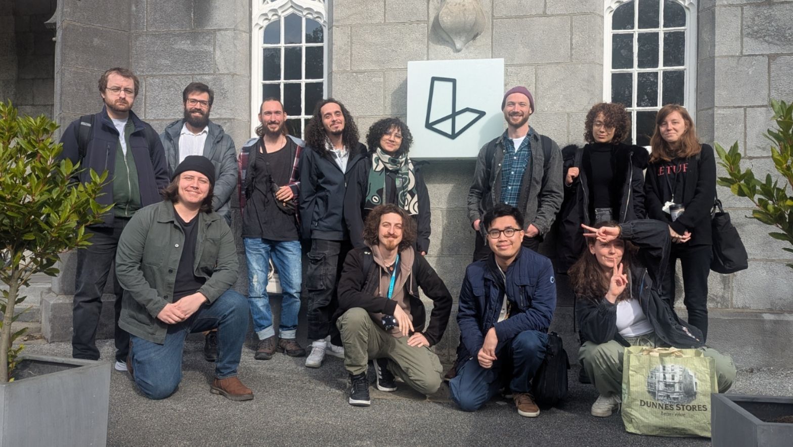 A group of individuals pose together in front of a building with a lightbox sign